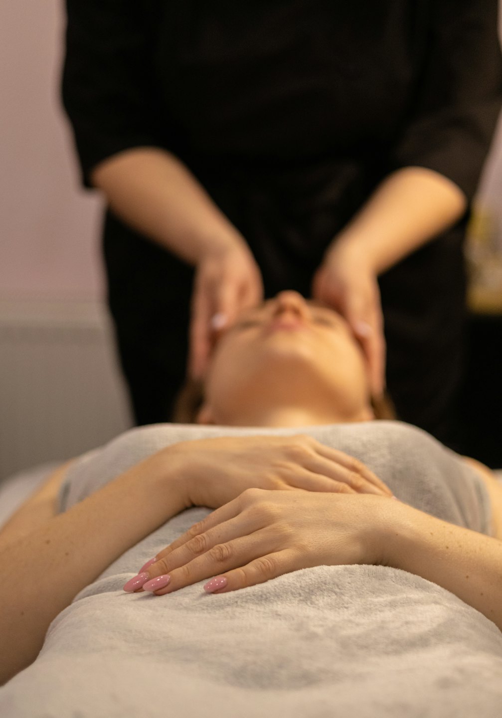 Un profesional de spa da un masaje facial a una mujer relajada.
